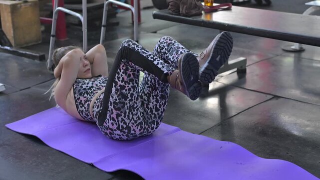 A Caucasian woman with cerebral palsy exercises in a gym.