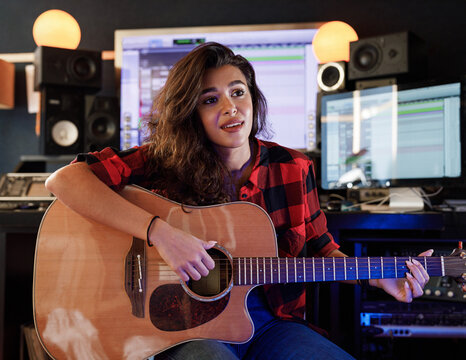 Woman with guitar rehearses song in studio