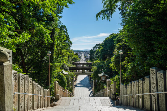 Stone staircase leading to Miyajidake Shrine with sun flare through trees in Fukutsu, Fukuoka, Japan
