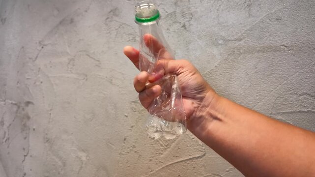 Close Up of Hand Crushing Plastic Water Bottle for Recycling