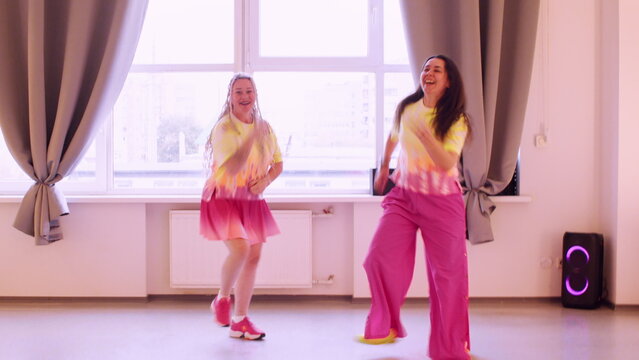 Positive dancer. Funny performance. Happy laughing woman in bright colorful clothes expressive moving in light studio with music speaker.