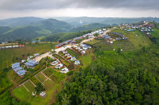 High aerial drone view of resort cottages spread over lush green mountain ridge in the morning at Mon Mork Tawan, Phop Phra, Tak, Thailand. Beautiful hillside travel destination.