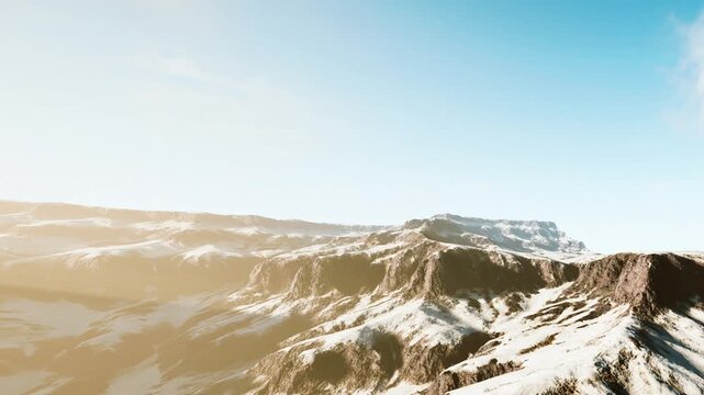 Mountains with patches of snow are visible under a bright blue sky. The warm afternoon light creates a clear view of the landscape. The scene captures the natural beauty of the area.