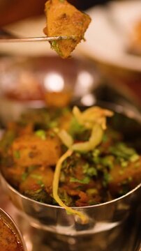 Person Eating Indian Aloo Gobi Curry with Fork in Restaurant