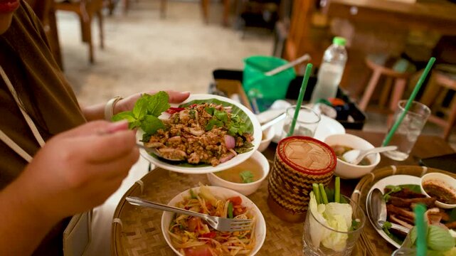 Person Eating Traditional Thai Isan Larb Moo and Papaya Salad
