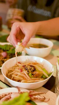 Hand Dipping Sticky Rice into Thai Papaya Salad Som Tum