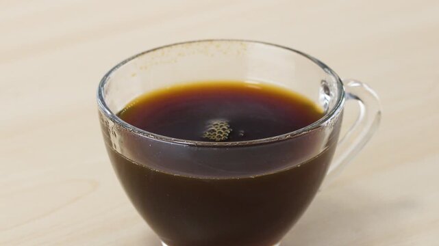 Dropping a Sugar Cube into a Glass Cup of Black Coffee