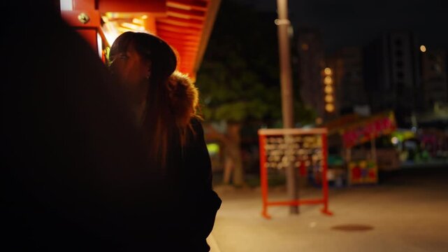 Young Asian woman travel traditional Japanese Sensoji Temple at night. Female tourist enjoy exploring culture sightseeing, winter tourism and local Japanese heritage experience on holiday vacation.