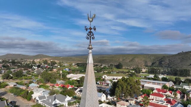 Aerial orbits rooster weathervane atop steeple in Uniondale S Africa