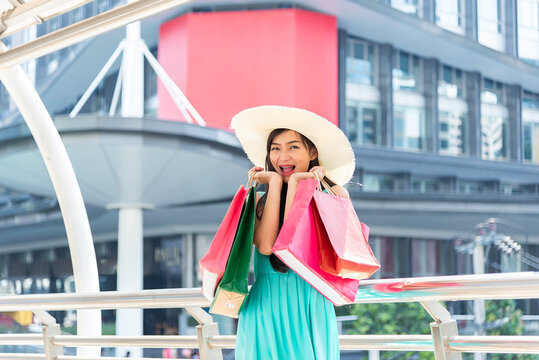 A young woman stands in the city with shopping bags and a sunny day A beautiful woman after shopping