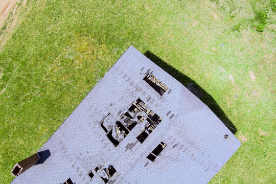 Aerial view roof of dilapidated structure with holes missing parts surrounded by green grass