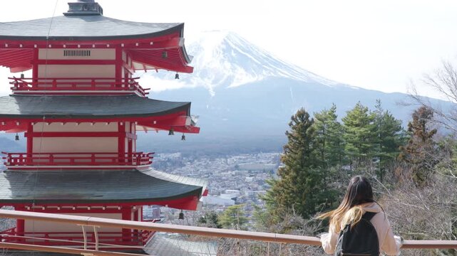 Asian woman tourist visiting Chureito Pagoda with Mount Fuji in Japan. Female traveler sightseeing traditional Japanese landmark, winter vacation, cultural tourism and scenic mountain travel