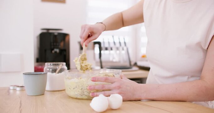 Cooking pastry. Kneading dough. Female chef hand spoon mixing ingredients for homemade cereal meal in glass bowl on kitchen countertop.