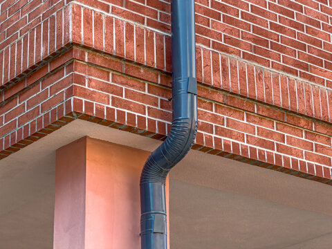 corner of renovated old industrial building with installed metal downspout.