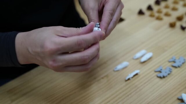 Close-up of hands assembling a multi-part novelty eraser figure at a Japanese workshop table