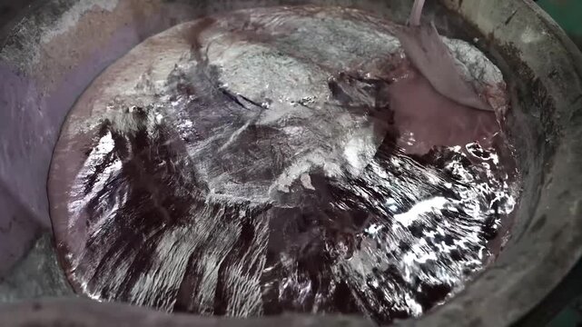Worker prying a rough cast aluminum part loose from a sand mold at a foundry
