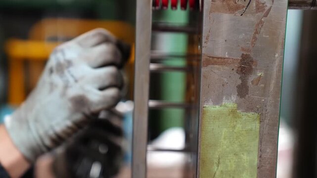 Worker adjusting a metal injection mold with red ejector pins during eraser manufacturing in Japan