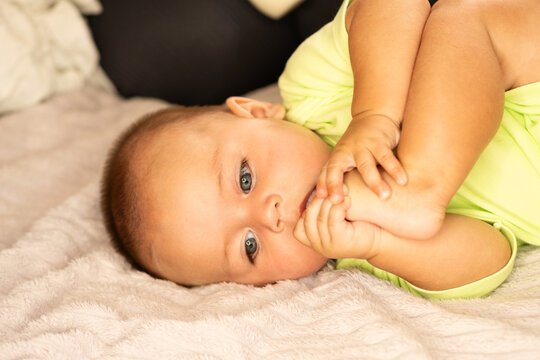 Curious Baby Boy Holds Bare Feet Near Mouth