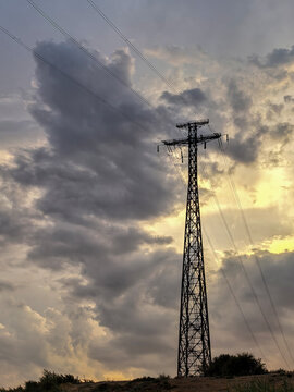 High Voltage Transmission Tower Against Stormy Sunset Sky