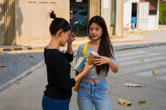 Two Asian students talking together during going classroom