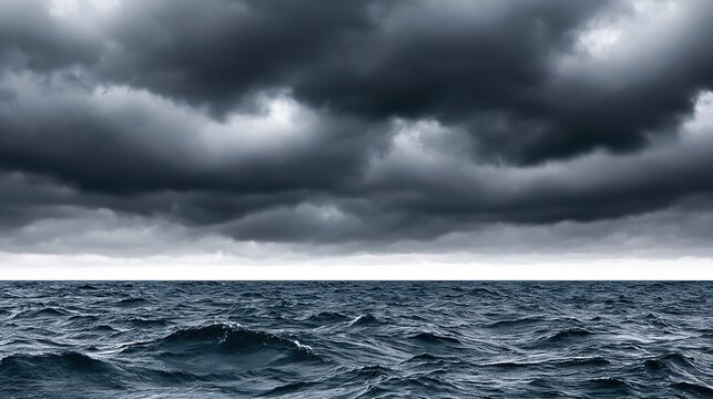 Dramatic moody seascape with heavy dark storm clouds over choppy deep blue ocean sea with small waves showing powerful extreme natural weather