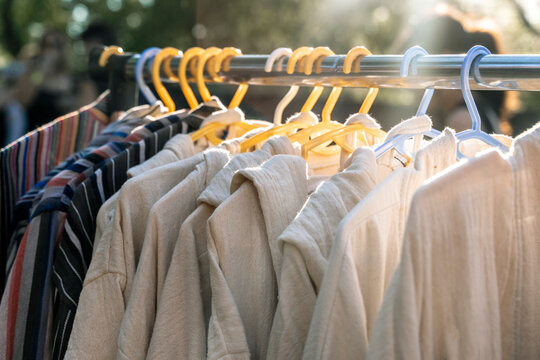 Clothing rack with hanging beige shirts and striped garments