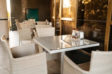 Fotobehang Horeca Elegant Outdoor Restaurant Terrace with White Wicker Chairs and Tables for Dining and Relaxation  © Gicu