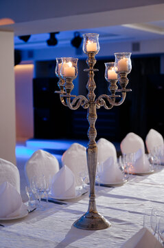 Elegant silver candelabra with lit candles on set dinner table for formal reception event