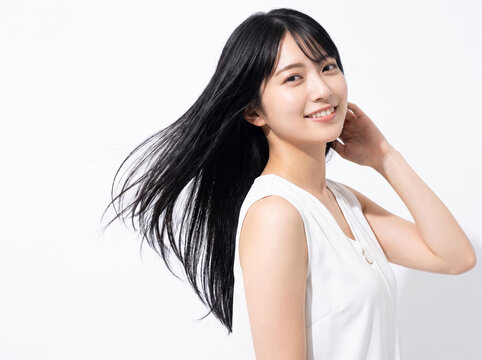 髪に手を添えて優しく微笑む白いVネック服の女性