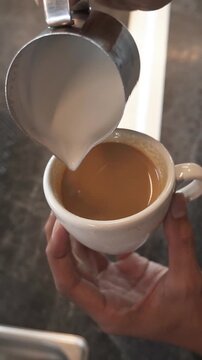 Steamed milk being poured into espresso to create a heart-shaped latte art design. Close-up footage of specialty coffee preparation and professional barista technique.