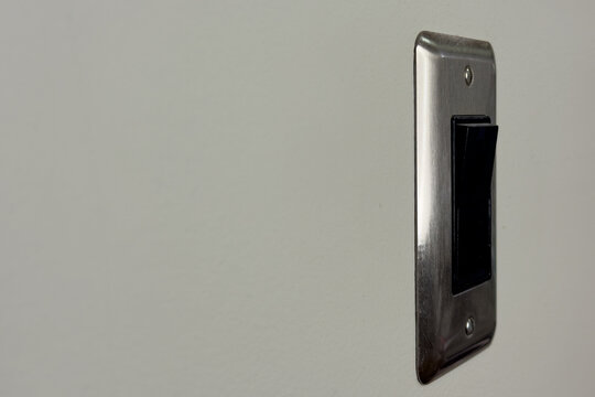 Light switch on wall in a room during the day displaying a simple design and basic functionality without any additional features