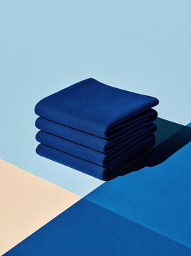 Folded stack of navy blue throws with a tactile cabled rib texture, set against a periwinkle and white background for product design and textile mockups