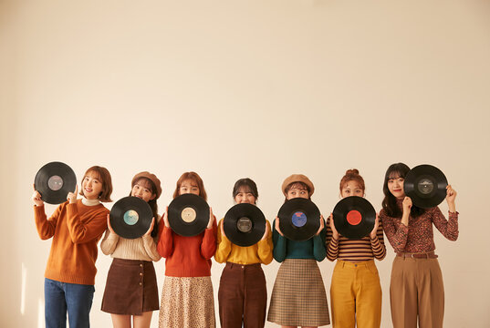 Group of eight diverse young women holding vinyl records smiling together