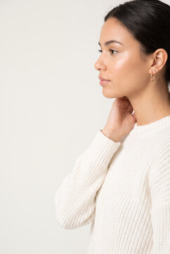 Young woman in white ribbed sweater looking thoughtfully away