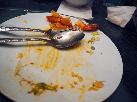 A dirty plate after a meal, with leftover food and used cutlery, suggesting a satisfied dining experience