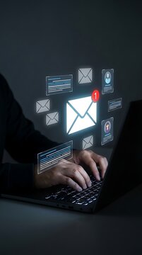 Person typing on a laptop in a dark room with a glowing digital interface showing email user profiles, and text document notifications