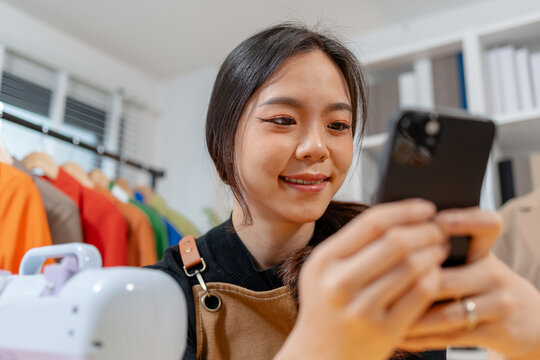 Professional fashion designer using a sewing machine in a modern studio while managing creative apparel production. Handmade craftsmanship, tailoring and small business workflow.