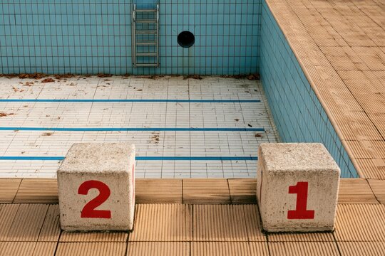 Empty tiled pool with starting blocks, ladders, and brown tiles