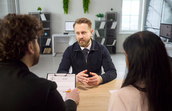 Interview meeting with HR recruiters and candidate. Managers lead discussion and review resume in a bright office. Evaluation covers skills, experience, and fit. Clear hiring concept in focus.