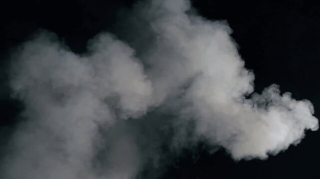 White smoke puff or vapor cloud rising and dissipating on a black background