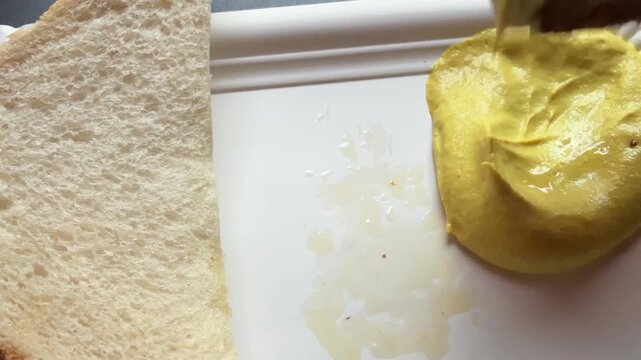 Personal perspective of a hand dipping meatball in mustard to eat German street food pov