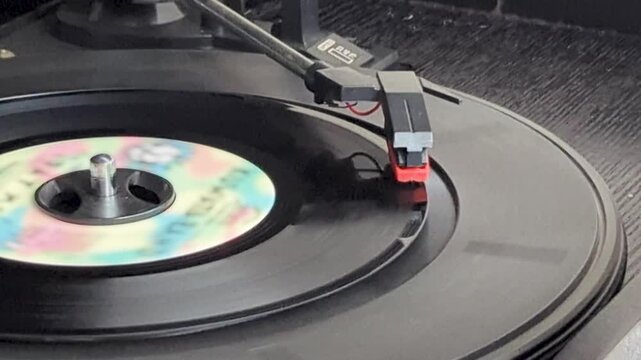 ターンテーブルで回転するドーナツ盤レコードと音楽を再生するレコード針（クローズアップ）