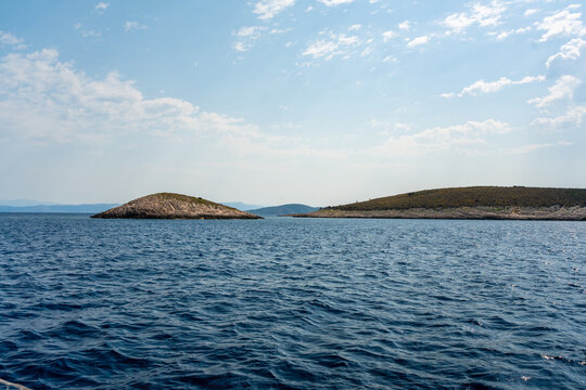 Small rocky islands surrounded by the Adriatic Sea under a blue summer sky. Peaceful coastal seascape with untouched Mediterranean nature.