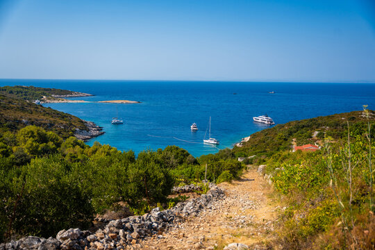 Scenic coastal bay with anchored yachts, turquoise Adriatic Sea, rocky shoreline and lush Mediterranean vegetation on Vis Island in Croatia. Ideal destination for sailing, boating and summer vacation