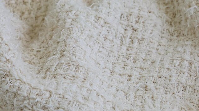 Beige knitted factory fabric texture, soft woven cotton or wool textile background, seamless neutral abstract material surface, gentle motion, cozy natural pattern.
