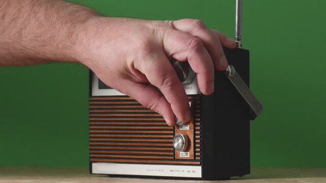 Switching on an old radio and tuning into different stations during - an authentic 70s radio