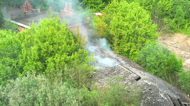Fire in one-story building with flames and smoke rising through the roof