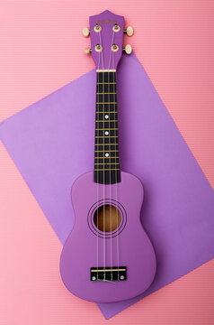Four-string ukulele guitar on a colored background, top view.