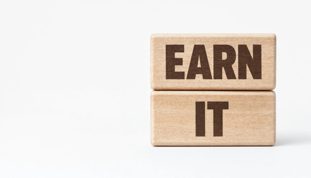 Earn it concept with wooden blocks stacked on white background symbolizing achievement and motivation