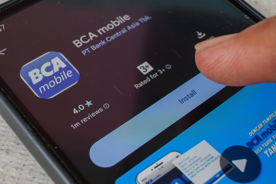 BCA mobile app page displayed on smartphone screen with finger touching install button, digital banking software download concept